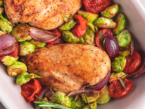 roasted chicken fillet with vegetables, brussels sprouts, onions, tomato close up