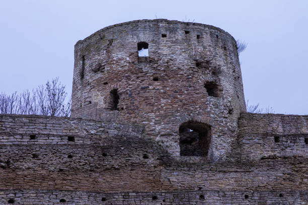 22 Feb 2020. Pskov, Russia. The ruines of old ancient medieval fortress or castle with turret or tower and brick, cobble or stone wall in the cloudy spring or autumn day