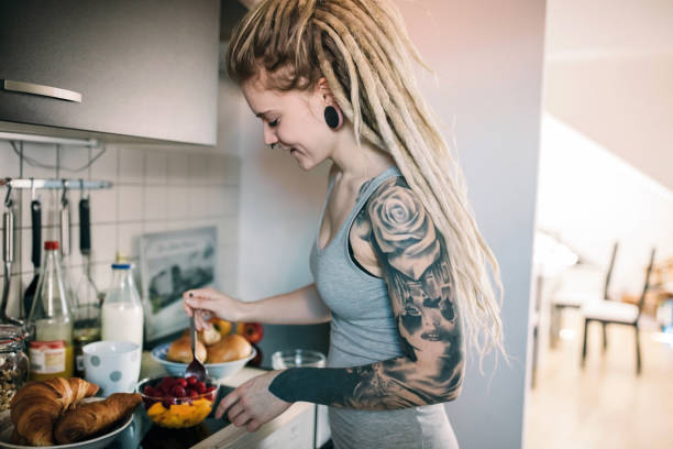 istock Young tattooed woman makes her breakfast in the kitchen 1219202065