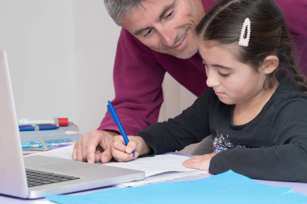 istock Homeschooling and distance learning. Elementary School. Dad helping the daughter in  homework during distance learning 1219203702
