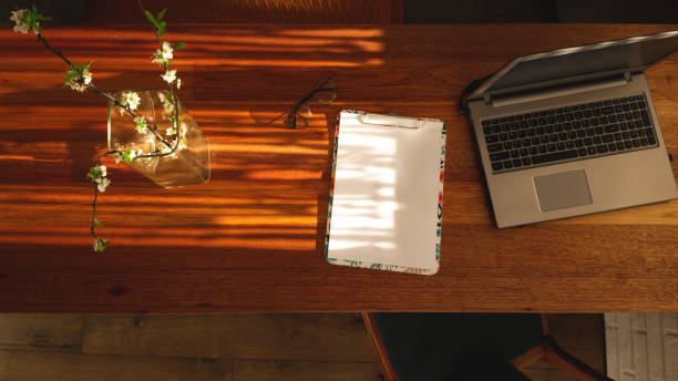 istock Minimalistic workplace at home on a wooden table in the shadows. 1219204161