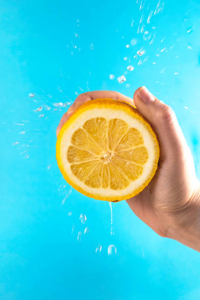 istock Yellow lemon in hand with drops of juice 1219204178
