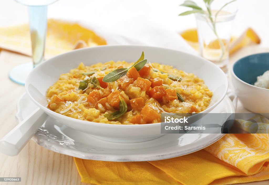 Delicious pumpkin risotto in a white bowl on wooden table pumpkin risotto with sage and parmesan Butternut Squash Stock Photo