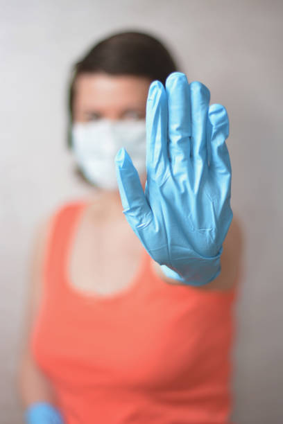 istock Woman with blue rubber glove make stop gesture. Soft focused. 1219206798