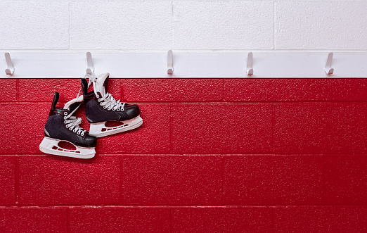Patines de hockey colgando sobre la pared roja en el vestuario con espacio de copia photo