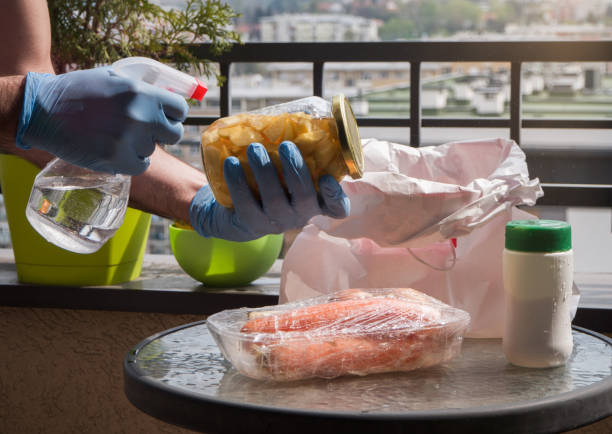 istock Man washing groceries with sanitizer spray and protective rubber gloves 1219210334