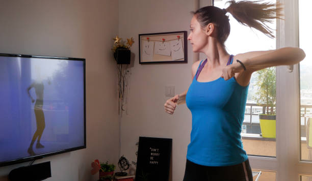 istock Woman exercising in front of tv and watching workout video 1219210482