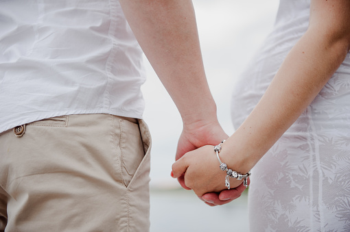 He and she are holding hands. A man is holding a woman's hand. Pregnant woman.