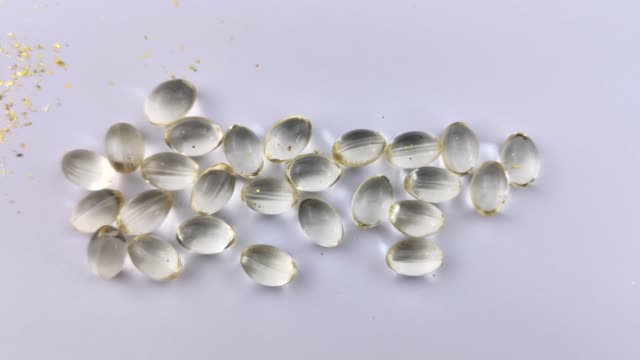Vitamin D3 capsules lie on a white background. The beam of light passes smoothly through the capsules creating an illusion of the internal glow of vitamins. Health care
