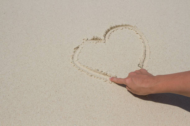 istock Heart drawn in the sand. Beach background. Top view 1219217632