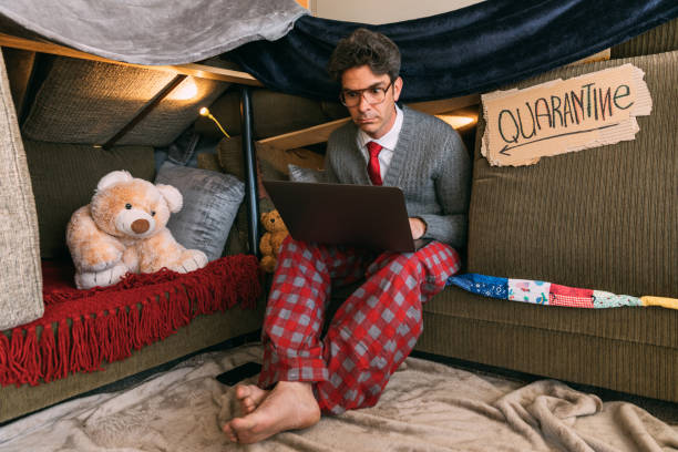 Nerd Teleworking from Home A hip nerd, who is under a shelter in place order, is teleworking from home. He is dressed in shirt and tie on the top, pajamas on the bottom while he works on his laptop from Quarantine. cheesy grin photos stock pictures, royalty-free photos & images
