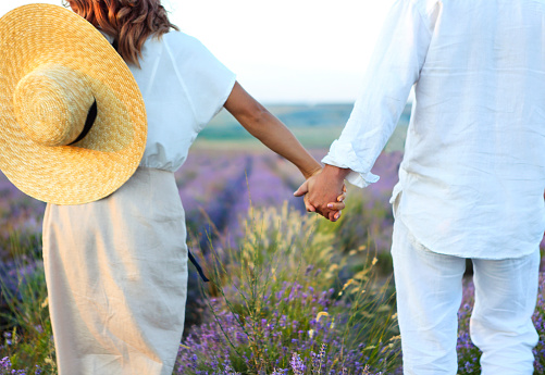 Cute young happy couple in love in a field of lavender flowers. Enjoy a moment of happiness and love in a lavender field. Romantic couple