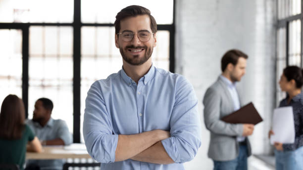 Smiling male CEO posing alone in modern office Smiling young Caucasian businessman in glasses stand in modern office show confidence and motivation at work, happy millennial European male CEO posing at workplace, leadership, success concept chief leader stock pictures, royalty-free photos & images