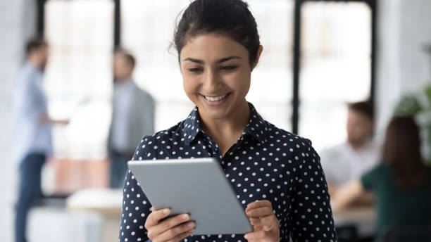 istock Smiling indian female employee use tablet at workplace 1219224638