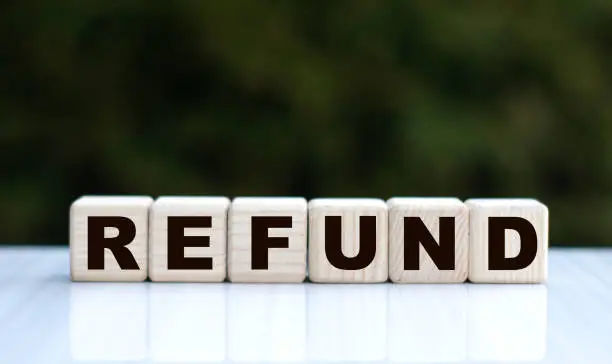 Photo of The concept of the word REFUND on cubes on a beautiful green background