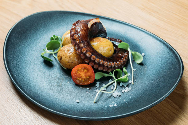istock grilled octopus tentacles, served with potatoes and vegetables tomatoes on a blue plate 1219227716