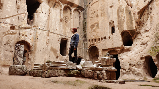 Man alone at ancient Gumusler Monastery surrounded by old stones and ruins in Gumusler, Nigde
