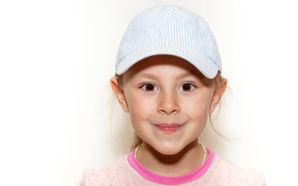 istock Preschool girl on white background with baseball hat looking at camera 1219231236