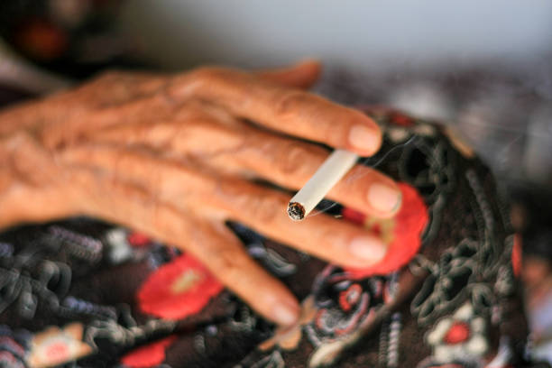 Old woman smoking cigarettes in hand stock photo