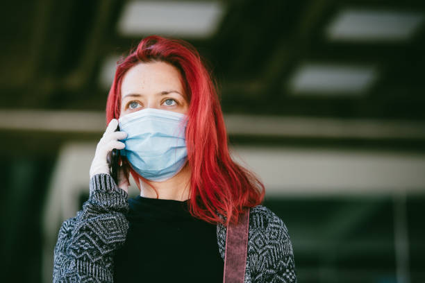 istock Woman wearing protective mask, using mobile phone 1219233604