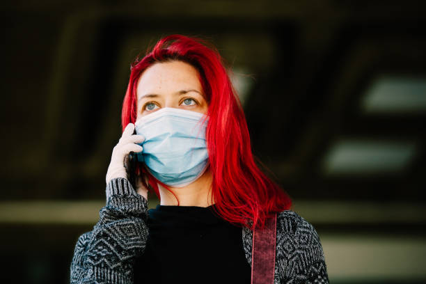 istock Woman wearing protective mask, using mobile phone 1219233661