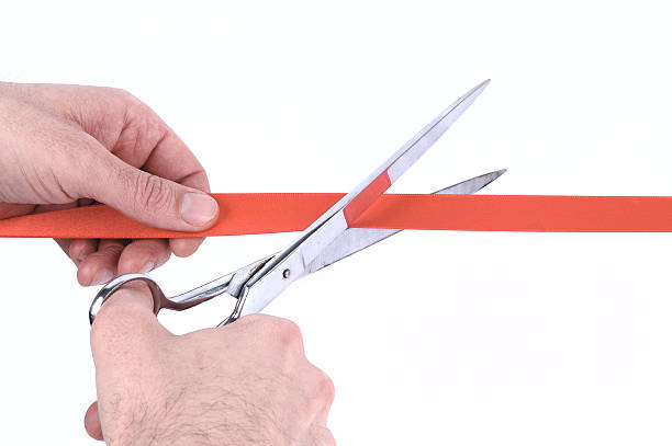 istock mans hand cutting a red ribbon with scissors 121923656
