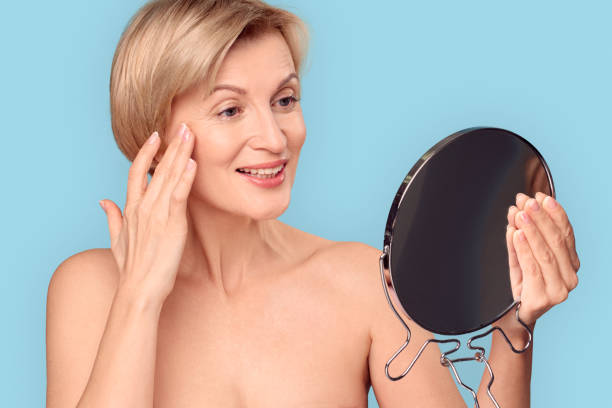 istock Middle aged woman looking at mirror, touching face 1219238692