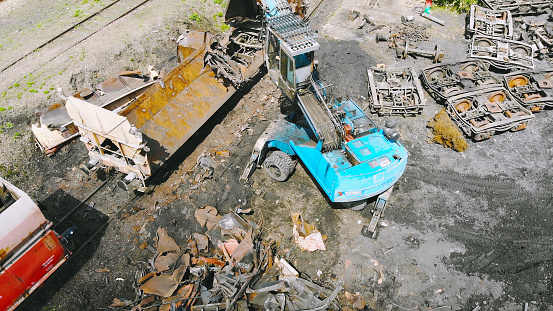 Heavy machinery working at scrapyard. Metal pieces lying on the ground