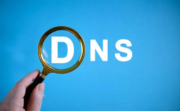 DNS - text with a magnifying glass on a blue background
