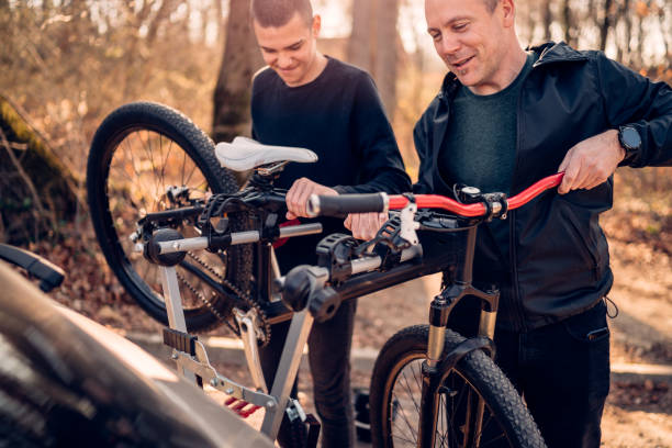 отец и сын взять велосипед вниз от стойки на машине - bicycle rack стоковые фото и изображения