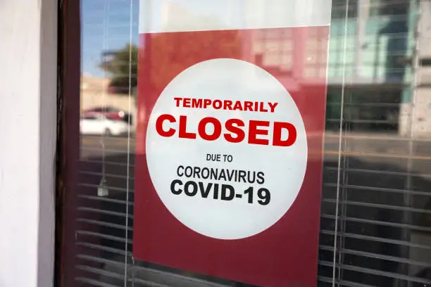 Store Temporarily Closed sign on the store's glass wall due to coronavirus pandemic.