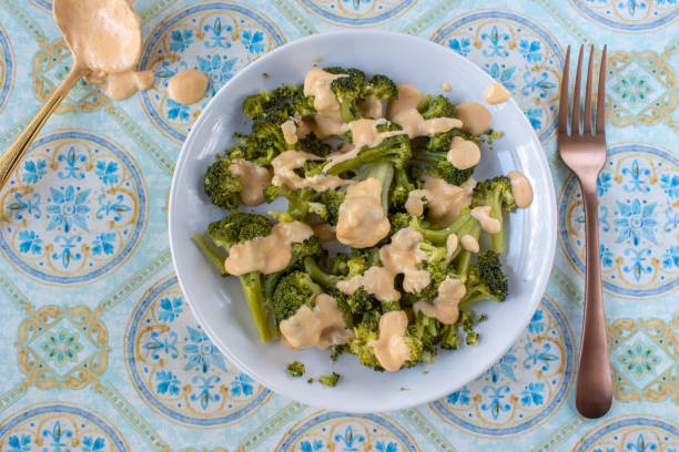plated steamed broccoli with cheese sauce on plate stock photo
