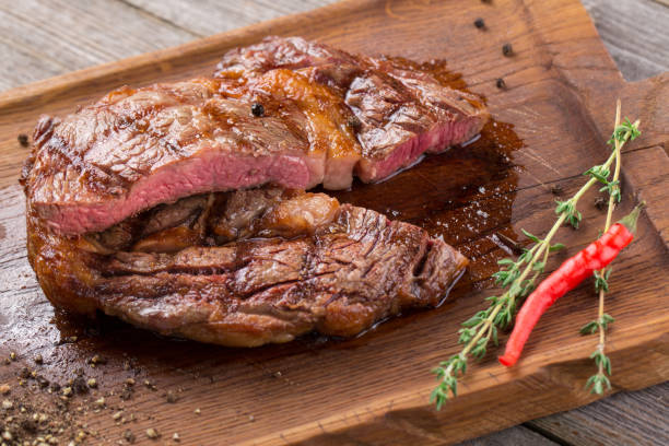 木製のボードにリブアイステーキをカット,クローズアップ.チリペッパーで飾られた木製ボード上のリブアイステーキ - rib eye steak beef cutting board meat ストックフォトと画像