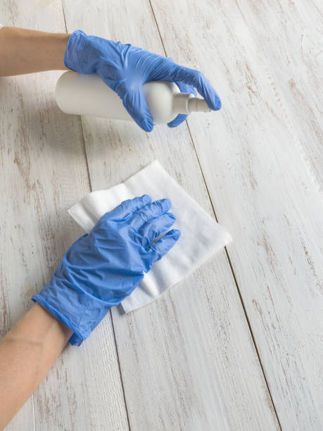 istock Surface cleaning spraying antibacterial sanitizing spray bottle disinfecting against COVID-19 spreading wearing medical blue gloves 1219247912