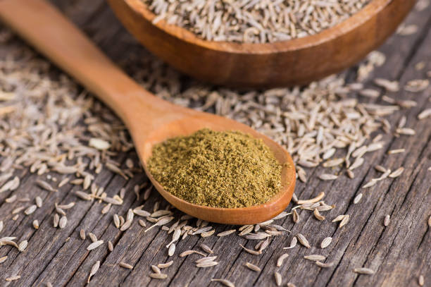 Pile of dry caraway spice with ground caraway powder in wooden spoon. Healthy food cumin spice concept ( Cuminum cyminum ) Pile of dry caraway spice with ground caraway powder in wooden spoon. Healthy food cumin spice concept ( Cuminum cyminum ) cumin stock pictures, royalty-free photos & images