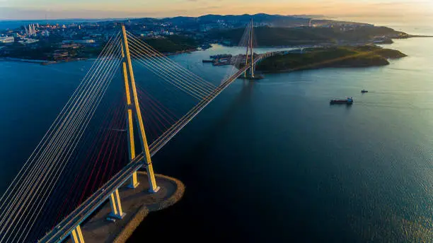 Amazing zooming out aerial view of the Russky Bridge, the world's longest cable-stayed bridge, and the Russky (Russian) Island in Peter the Great Gulf in the Sea of Japan. Sunrise. Vladivostok, Russia