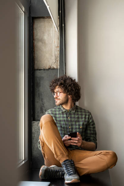 istock Happy Casually Dressed Millenial Texting on his Smartphone at Work 1219255166