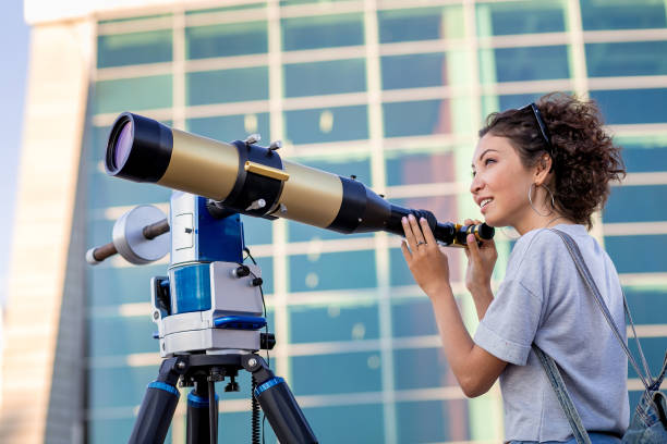 istock girl looking through a telescope outdoors 1219255230