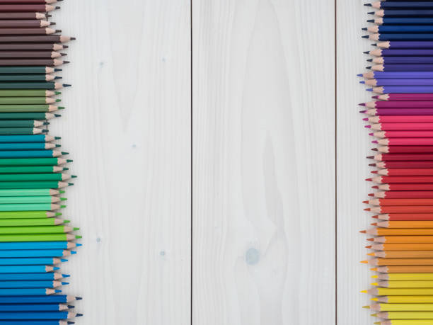 two rows of colored pencils on wooden background