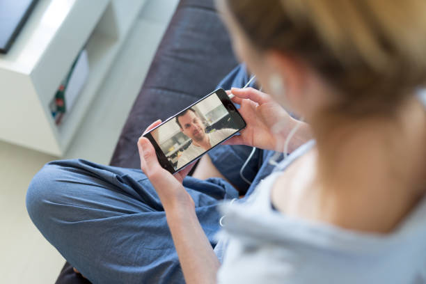 istock Woman at home relaxing on sofa couch using social media on phone for video chatting with her loved ones during corona virus pandemic. Stay at home, social distancing lifestyle. 1219258526