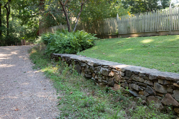 muro di contenimento in pietra naturale lungo un sentiero di ghiaia, erba verde e stretta recinzione di picchetto - picket fence grass gardens nature foto e immagini stock