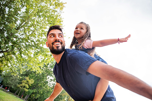 happy father giving his little daughter a piggy back ride