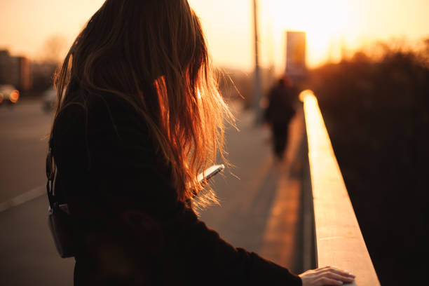 istock Young woman using smart phone in city at sunset 1219265142