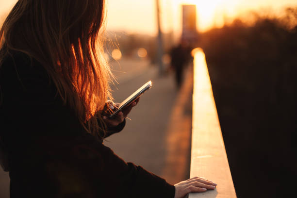 istock Young woman using smart phone in city at sunset 1219265657