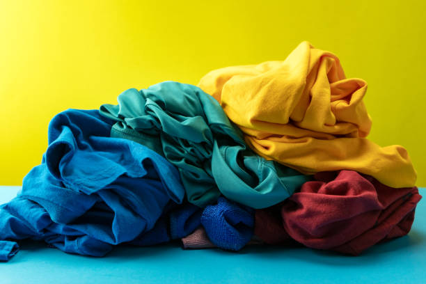 istock Pile of dirty laundry clothes on blue table Yellow light background. 1219272946