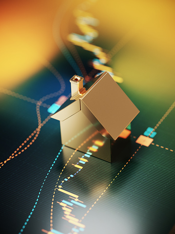 Gold colored house symbol sitting over a bar graph. Selective focus. Vertical composition with copy space. Mortgage and finance concept.
