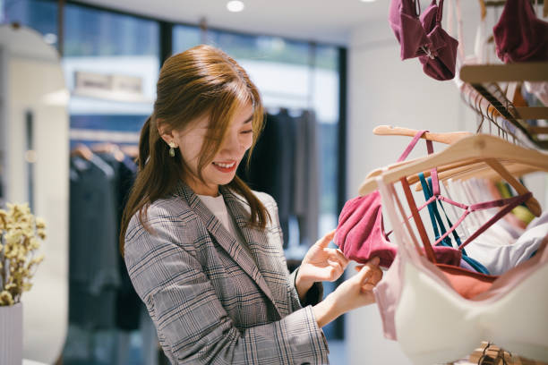 młoda azjatka wybiera nowy biustonosz w sklepie odzieżowym. - retail shopping bra underwear zdjęcia i obrazy z banku zdjęć