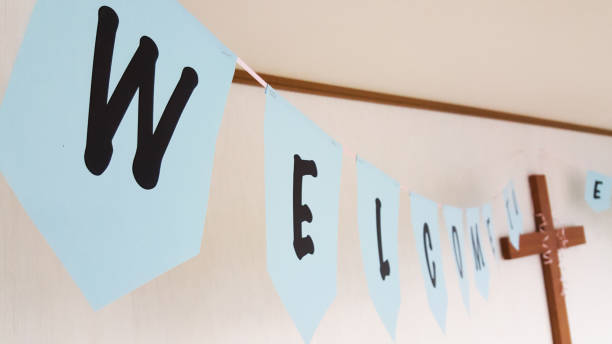 Welcome sign hanging next to the wooden cross on the wall at church event for children.