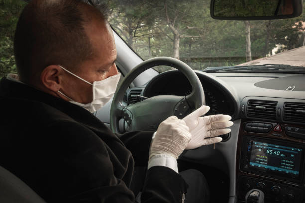 A senior adult trying to wear his surgical gloves in his car for protection stock photo