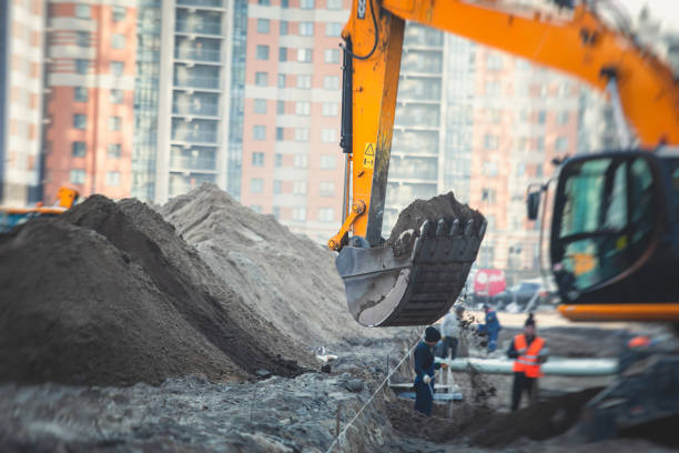 istock Yellow heavy excavator excavating sand and working during road works, unloading sand during construction of the new road with workers around 1219286775